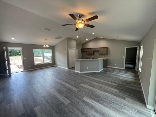 unfurnished living room with ceiling fan with notable chandelier, dark wood-type flooring, and lofted ceiling