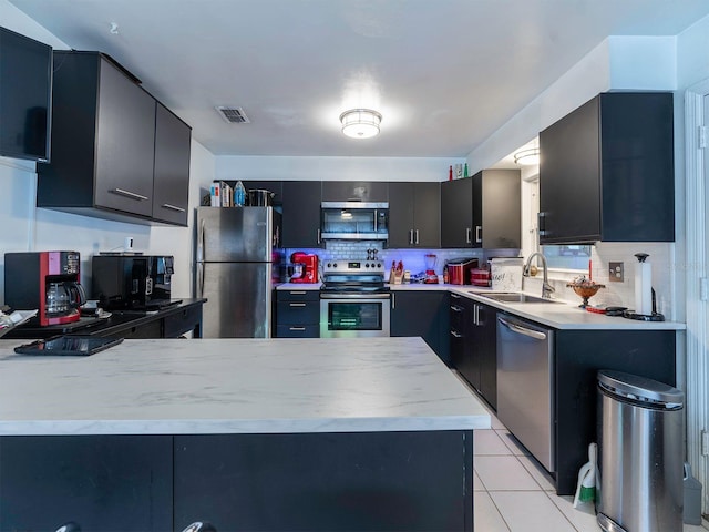 kitchen featuring light tile flooring, kitchen peninsula, tasteful backsplash, appliances with stainless steel finishes, and sink