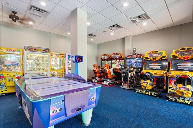 recreation room featuring a drop ceiling and dark colored carpet