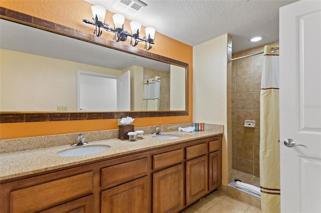 bathroom with vanity, curtained shower, a textured ceiling, and tile patterned flooring