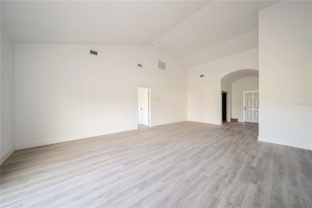 empty room featuring high vaulted ceiling and light hardwood / wood-style floors