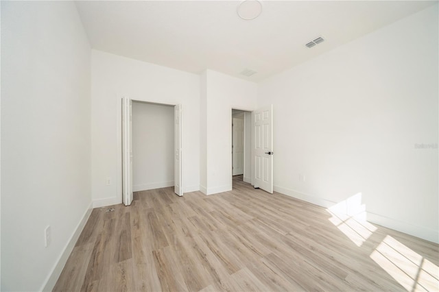 unfurnished bedroom with a closet and light wood-type flooring