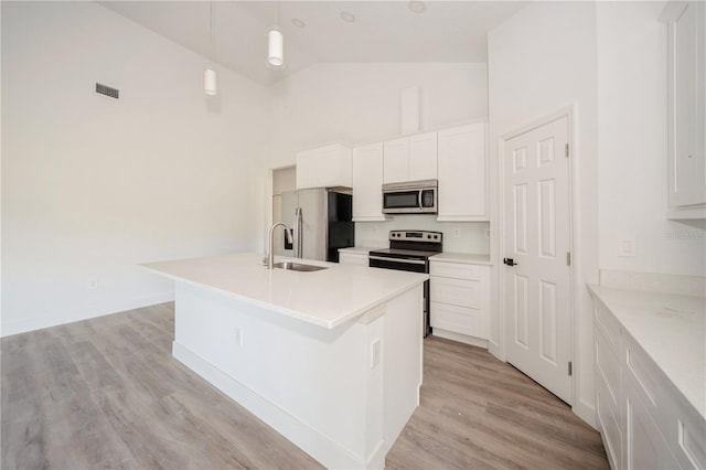 kitchen with decorative light fixtures, an island with sink, stainless steel appliances, high vaulted ceiling, and white cabinets