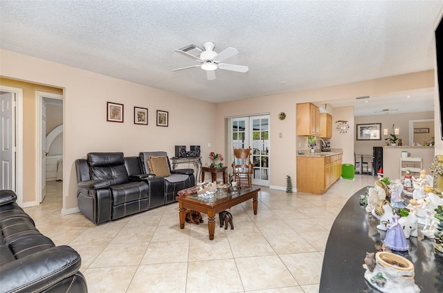 living room with ceiling fan, a textured ceiling, and light tile floors