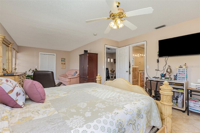 tiled bedroom with connected bathroom, ceiling fan, and a textured ceiling