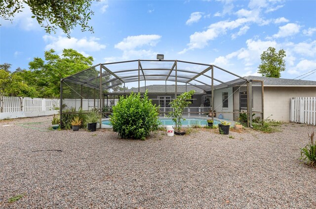 back of property with glass enclosure and a fenced in pool