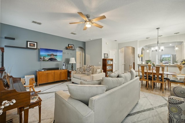 carpeted living room with ceiling fan with notable chandelier and a textured ceiling