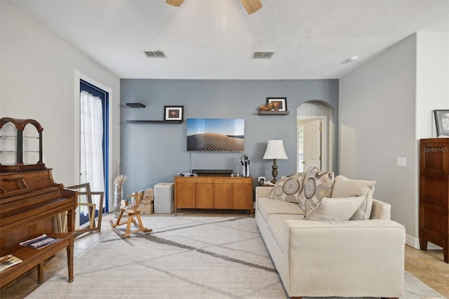 tiled living room featuring ceiling fan and a textured ceiling