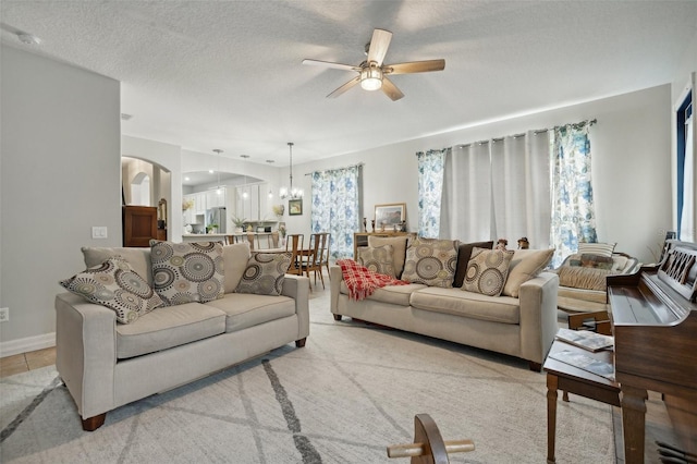 living room with a textured ceiling, carpet floors, and ceiling fan with notable chandelier