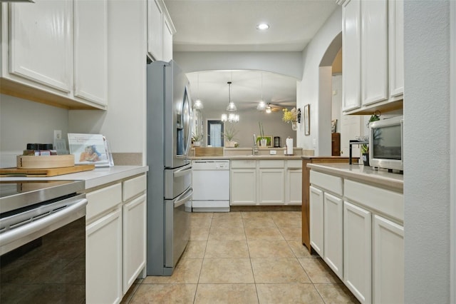 kitchen with kitchen peninsula, hanging light fixtures, white cabinets, light tile floors, and appliances with stainless steel finishes