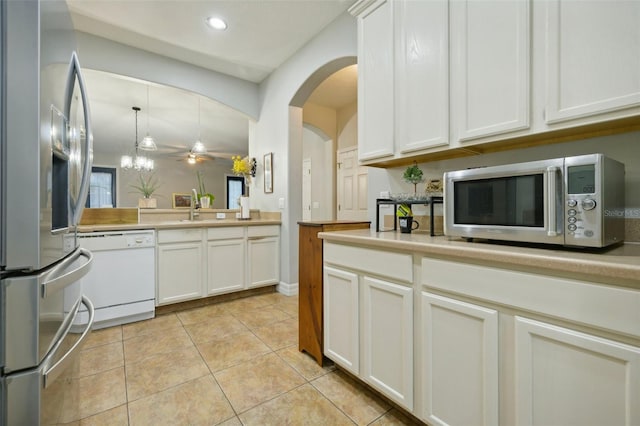 kitchen featuring hanging light fixtures, appliances with stainless steel finishes, white cabinets, sink, and light tile flooring