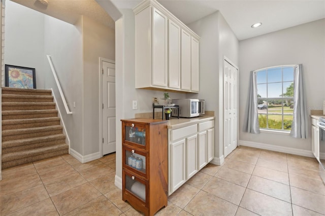 kitchen with butcher block counters, white cabinetry, and light tile floors