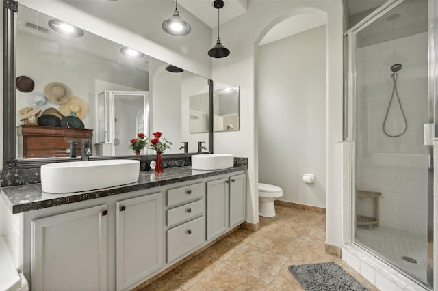 bathroom with a shower with shower door, tile flooring, vanity with extensive cabinet space, and dual sinks