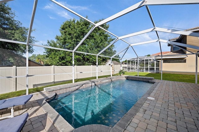 view of swimming pool featuring a lawn, a patio area, and a lanai