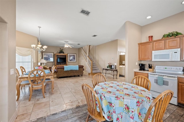 dining space featuring ceiling fan with notable chandelier