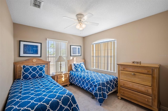 carpeted bedroom featuring a textured ceiling and ceiling fan