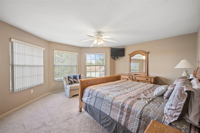 carpeted bedroom with ceiling fan and a textured ceiling