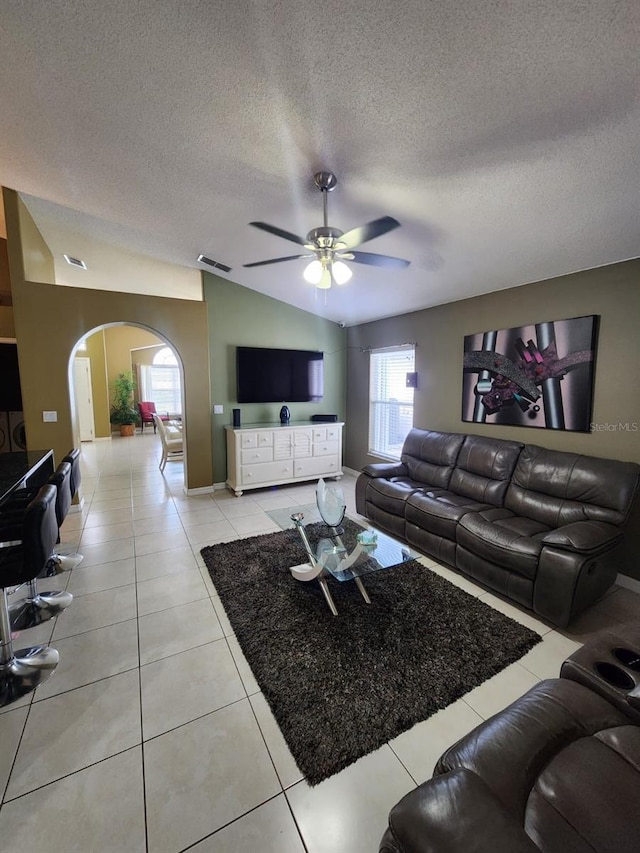 tiled living room with lofted ceiling, a textured ceiling, and ceiling fan