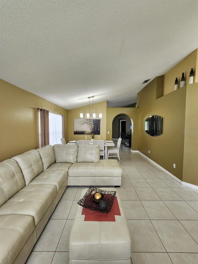 tiled living room with lofted ceiling, a textured ceiling, and a notable chandelier