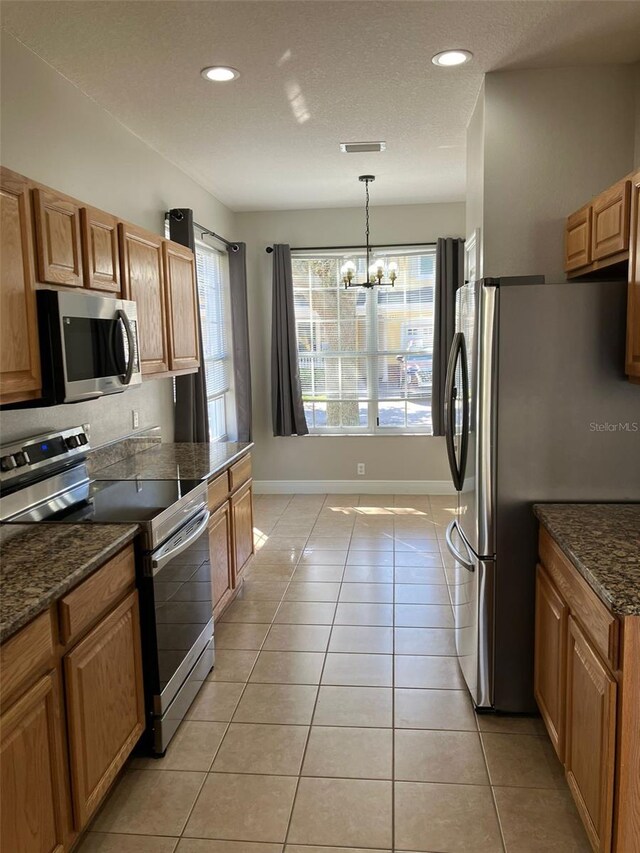 kitchen featuring a notable chandelier, pendant lighting, light tile floors, and stainless steel appliances