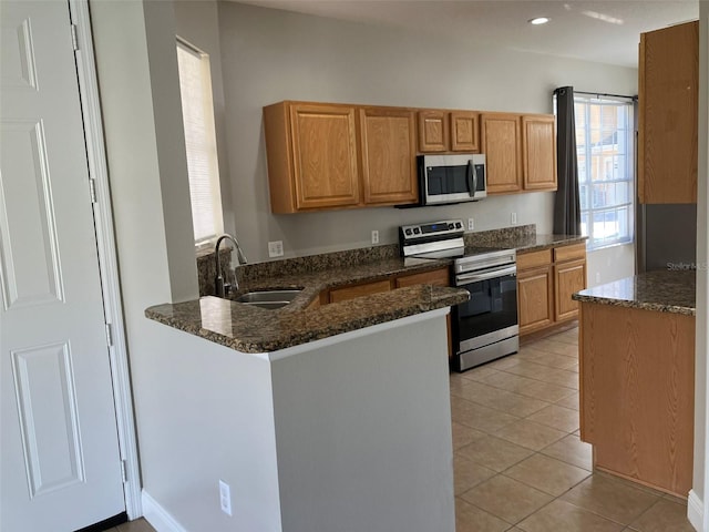 kitchen featuring kitchen peninsula, electric stove, dark stone countertops, light tile floors, and sink