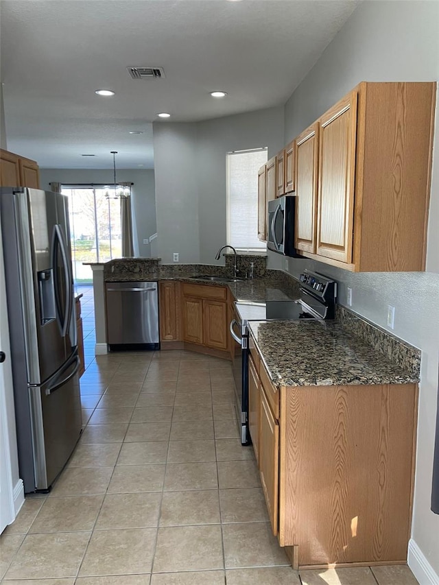 kitchen with dark stone countertops, sink, light tile flooring, and appliances with stainless steel finishes