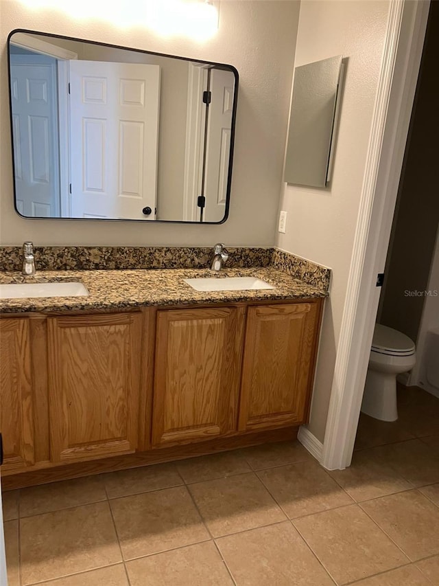 bathroom with tile floors, toilet, and double sink vanity