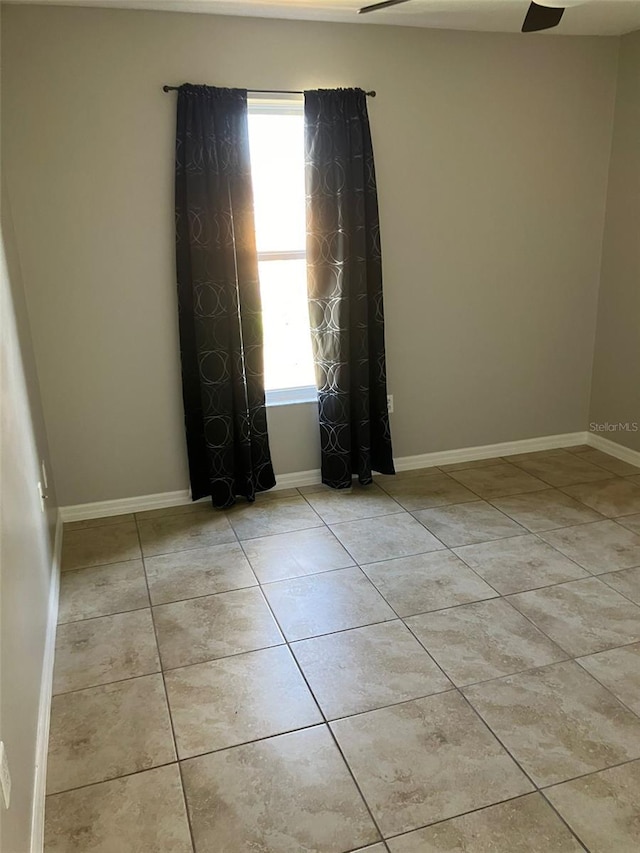 tiled spare room featuring ceiling fan and a healthy amount of sunlight