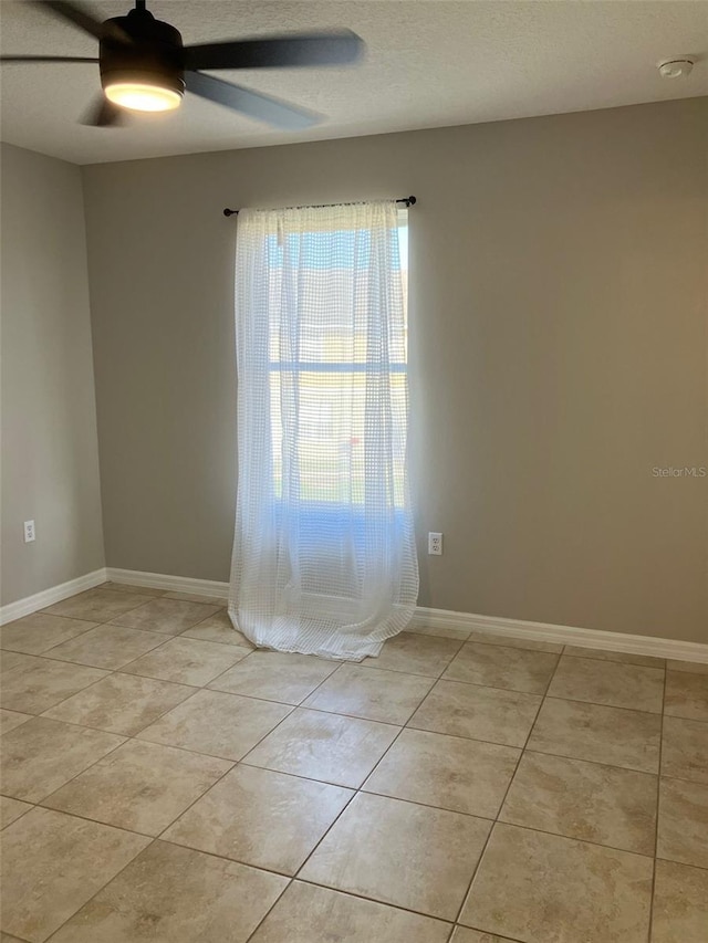 empty room with ceiling fan and light tile floors