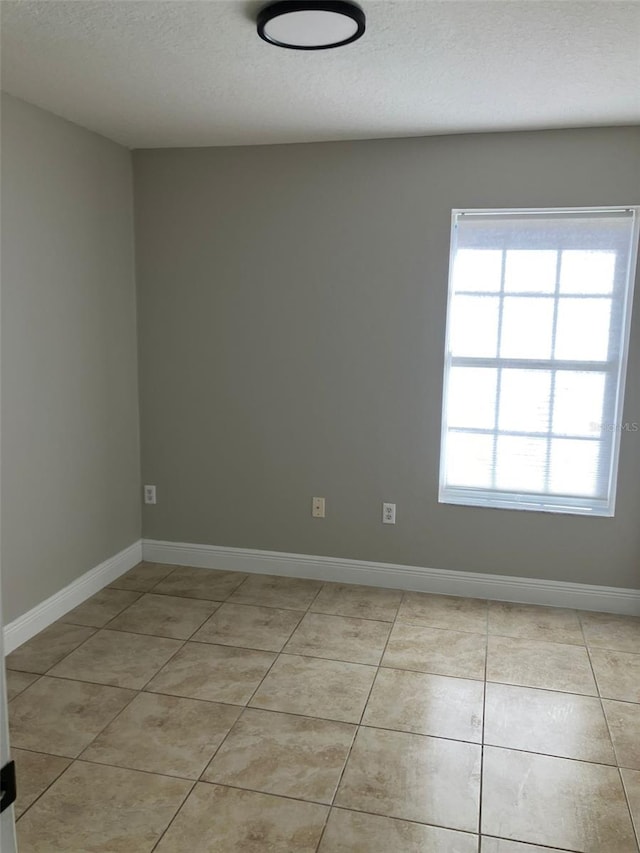 tiled empty room with a textured ceiling and plenty of natural light