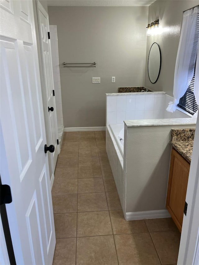 bathroom with tile floors, tiled tub, and vanity