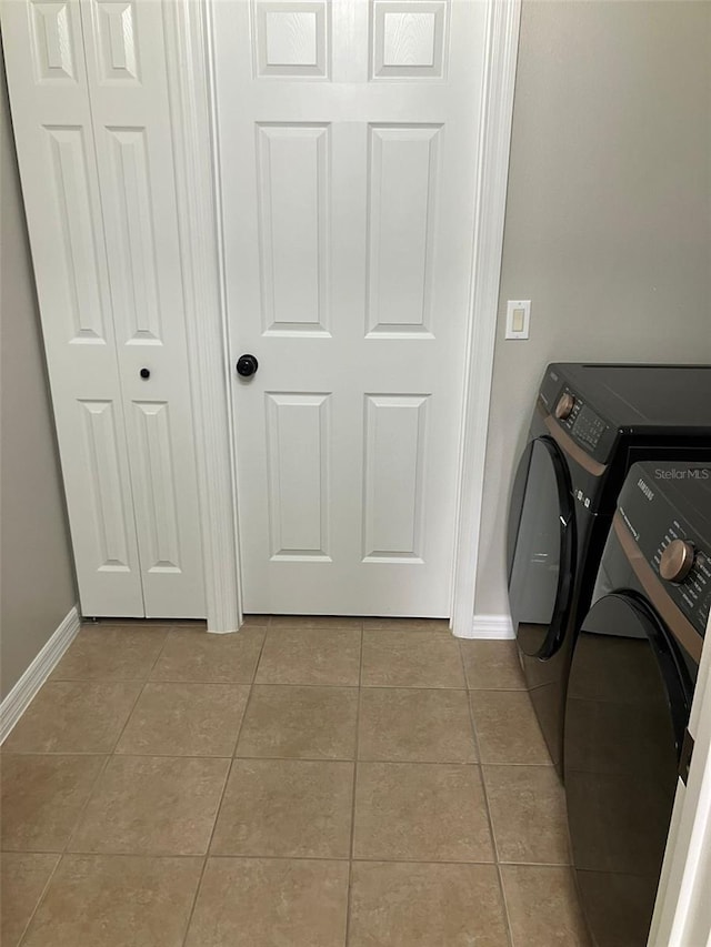 clothes washing area featuring washer and dryer and light tile floors