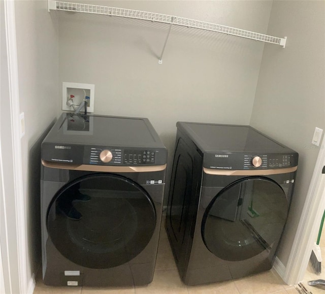 laundry area featuring washer hookup, light tile floors, and washing machine and clothes dryer