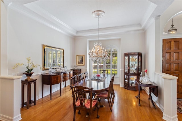 dining area with a tray ceiling and light wood-type flooring