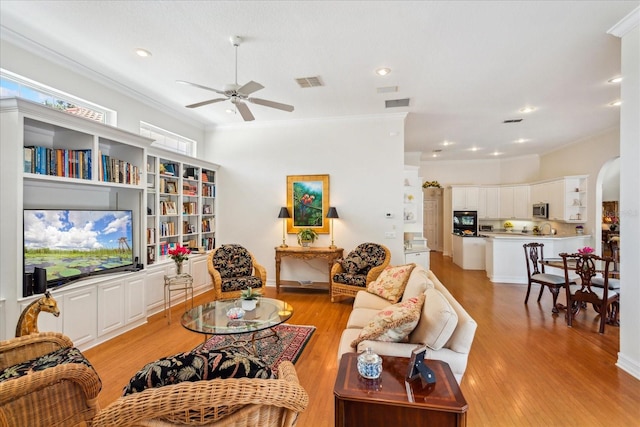 living room with light hardwood / wood-style floors, crown molding, and ceiling fan