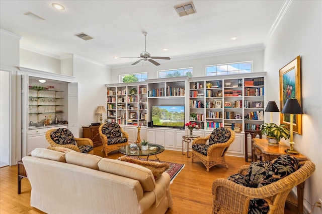 living room featuring crown molding, light hardwood / wood-style flooring, and ceiling fan