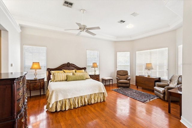 bedroom with hardwood / wood-style flooring, a tray ceiling, and ceiling fan