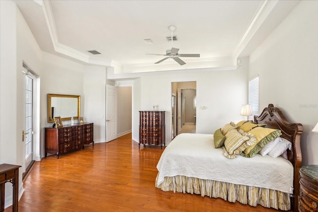 bedroom featuring ceiling fan, hardwood / wood-style flooring, a tray ceiling, and crown molding