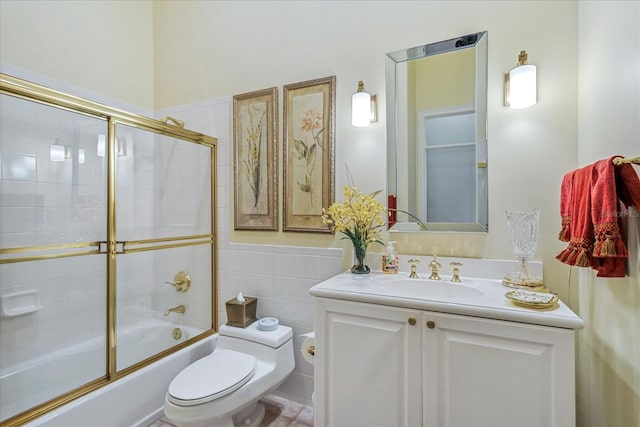 full bathroom with combined bath / shower with glass door, tile walls, toilet, vanity, and tile patterned floors