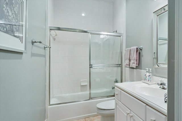 full bathroom featuring vanity, shower / bath combination with glass door, toilet, and tile patterned flooring