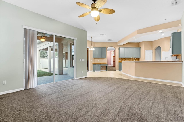 unfurnished living room featuring ceiling fan, sink, and light carpet