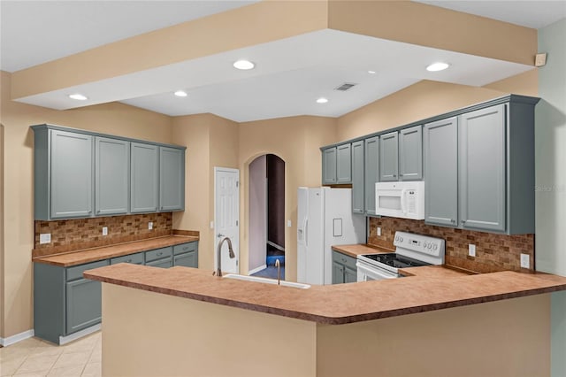 kitchen featuring white appliances, decorative backsplash, gray cabinets, light tile patterned flooring, and kitchen peninsula