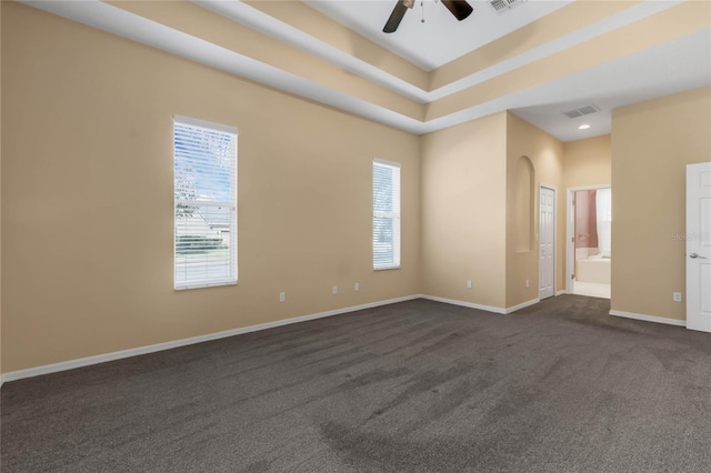 carpeted spare room with ceiling fan, a raised ceiling, and a wealth of natural light