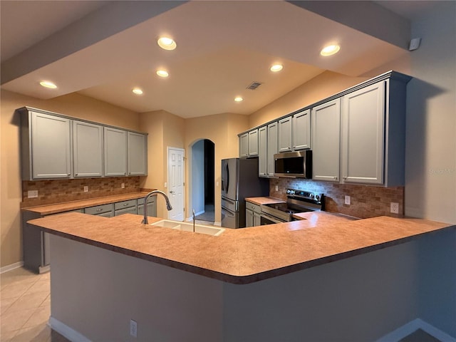 kitchen with gray cabinetry, sink, kitchen peninsula, and appliances with stainless steel finishes