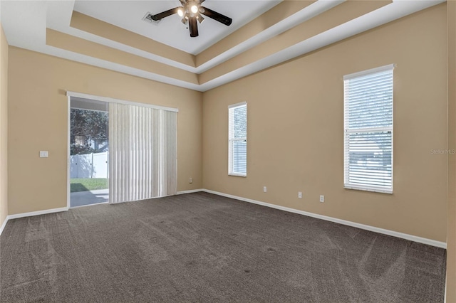 unfurnished room featuring a raised ceiling, ceiling fan, and carpet flooring