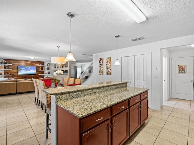 kitchen featuring hanging light fixtures, a center island, a textured ceiling, and light tile floors