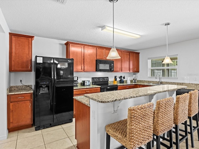 kitchen with a breakfast bar, black appliances, sink, and pendant lighting