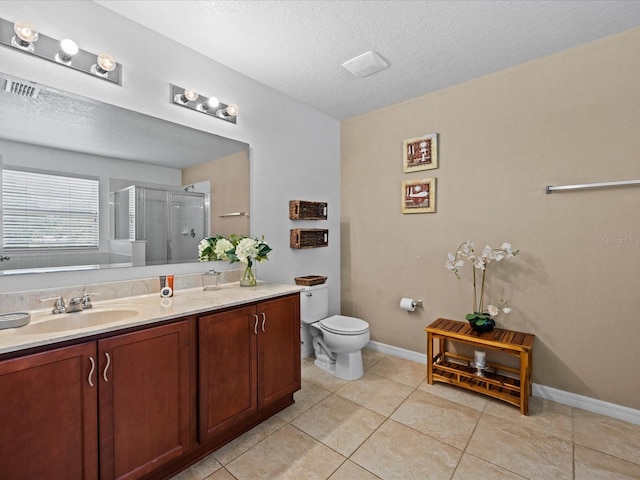 bathroom with tile flooring, vanity, toilet, and a textured ceiling