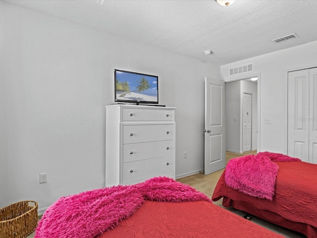 bedroom with a textured ceiling and light colored carpet