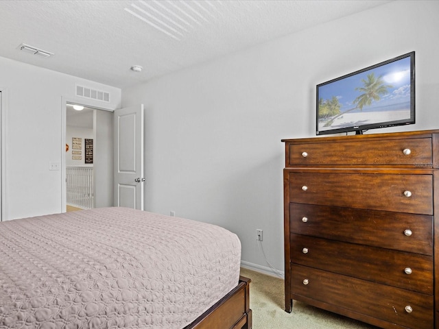 bedroom featuring a textured ceiling and light colored carpet